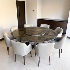 a dining room table with white chairs and a round wooden table in front of it