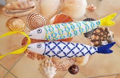 three stuffed fish are sitting on top of seashells and other sea creatures in the background