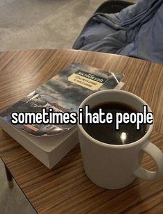 a cup of coffee sitting on top of a wooden table next to a paperback book