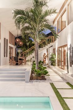 an indoor swimming pool with stairs leading to the upper floor and palm trees in the background