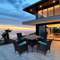 an outdoor dining table and chairs on a deck overlooking the ocean at sunset or dawn