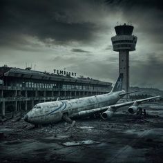 an airplane that is sitting on the ground in front of a building with a tower behind it