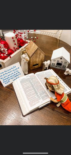 an open book sitting on top of a wooden table next to christmas decorations and other items