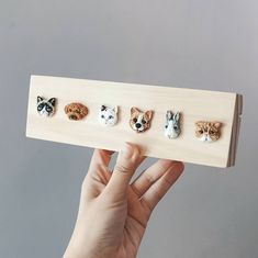 a person holding up a piece of wood with four small dogs on it