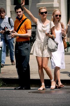 a man and woman walking down the street with their arms in the air while one holds up her hand