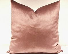 a pink pillow sitting on top of a white couch