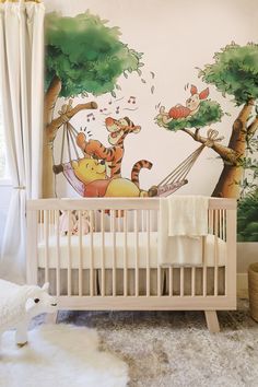 a baby's room with winnie the pooh mural and crib bedding