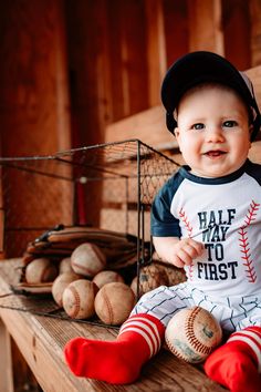 a baby sitting on top of a wooden bench next to baseballs