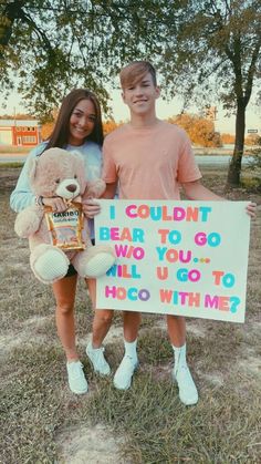 two people standing in the grass holding a sign with a teddy bear and an i couldn bear to go who you, all u go to hoo - go to hoo with me?