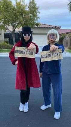 two people dressed in costumes holding up golden ticket signs while standing next to each other