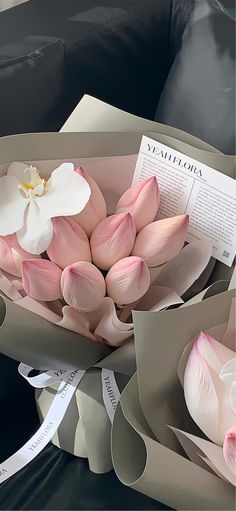 a bouquet of pink and white flowers sitting on top of a black table next to a card