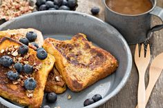 french toast with blueberries and walnuts on a gray plate next to a cup of coffee