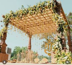 an outdoor wedding setup with flowers and greenery hanging from the ceiling, surrounded by wooden pillars