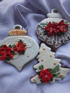 three decorated cookies sitting on top of a blue cloth covered table with poinsettis