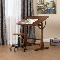 a small wooden desk with a magazine on it and a chair next to it in front of a window