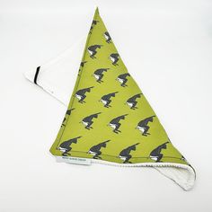 a green bandana with black and white birds on it's side, sitting on a white surface