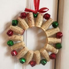 a wreath made out of wine corks hanging on a door with red and green ribbon