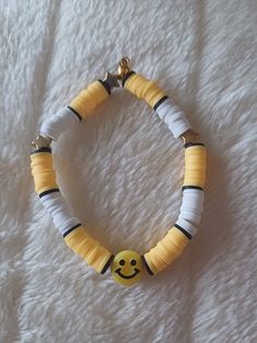 a yellow and white bracelet with a smiley face on it