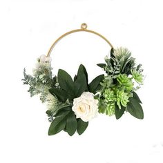 white flowers and greenery are arranged in a circular wreath on a white background with gold hoop