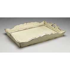 an old white tray with scalloped edges on the bottom and handles is shown