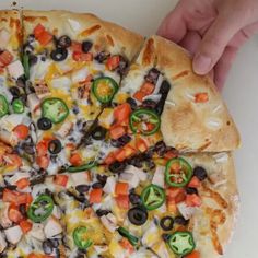 a pizza with several toppings on it being held by two hands