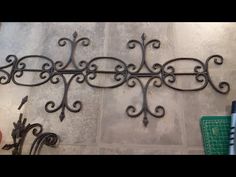 a wrought iron wall hanging on the side of a tiled floor next to a cutting board and scissors