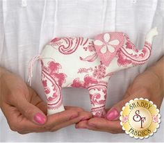 two hands holding a pink and white elephant