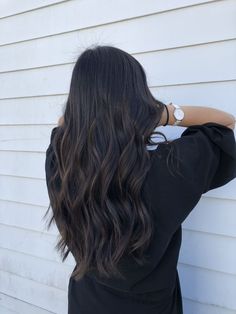 the back of a woman's head with long, wavy hair in front of a white house