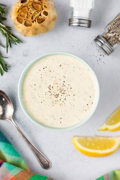 a bowl filled with cream next to lemons and spices