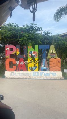 a sign that says pinata cay in front of some trees and bushes behind it