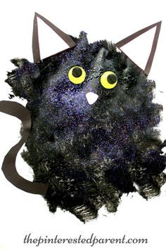 a black cat with yellow eyes on it's face is made out of paper