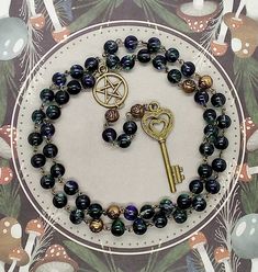 This nontraditional 5 decade rosary is made up of gorgeous 6 mm glass beads.  Each bead has splashes of green and blue. The decades are divided by bronze rose shaped beads.   This string is hand wired together with bronze wire.   The centerpiece is a bronze pentacle, and at the bottom hangs a bronze key with a heart shaped top. The full prayer string measures 19 inches long when hanging. Upon purchase, your prayer beads will be shipped within 5 business days. For US purchasers, I use USPS Ground Advantage Mail with tracking with the option to upgrade to paid Priority shipping during the purchase process.  Orders being shipped outside the US will be sent via USPS First Class Mail International. Thank you for looking! Spiritual Rosary Bracelet With 108 Beads As Gift, Spiritual Beaded Rosary As Gift, Spiritual Wire Wrapped Rosary As Gift, Spiritual Gift Wire Wrapped Rosary, Heart Shaped Top, Pagan Gifts, Pagan Prayer Beads, Crystal Rosary, Pagan Prayer