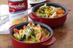 two red bowls filled with food sitting on top of a wooden table next to a can of soup