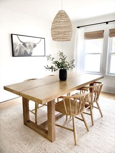 a dining room table with four chairs and a plant in the center on top of it