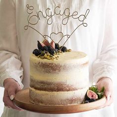 a person holding a cake with the word yay on top and berries on it