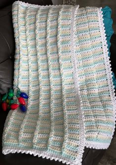 a crocheted blanket sitting on top of a couch next to a pile of toys