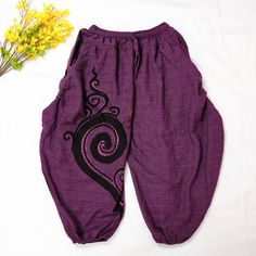 a pair of purple pants with black swirls on them and yellow flowers next to it