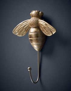 a gold bee hook on a wall with a hook in the shape of a honeybee