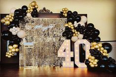 a black and gold balloon arch with the number forty on it, surrounded by balloons