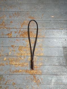 an old black leash laying on top of a wooden floor