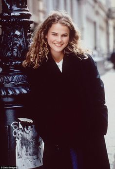 a woman standing next to a black pole