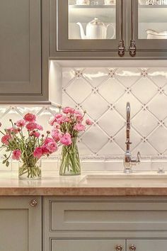 pink flowers are in vases on the kitchen counter