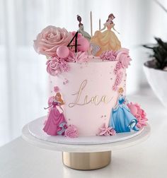 there is a pink cake decorated with princesses and flowers on the top of it