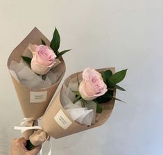 two pink roses are wrapped in brown paper