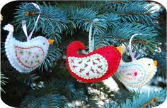 three ornaments hanging from a christmas tree in the shape of two birds, one red and one white