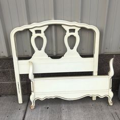 an old white bed frame sitting in front of a wall