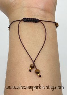 This beautifully handmade bracelet is made of round medium 4mm Brown tiger's eye beads sectioned by small gold colored beads and with a glass evil eye bead (choice of color). The bracelet is made with brown thread string and are adjustable to fit most wrists as it has a sliding knot drawstring to adjust. These are a great accessory for everyday wear for both men and women. Tiger's eye crystal is a beautiful bead with bands of brown and golden colors. It is believed that this stone helps to maint Adjustable Rosary Bracelet With 8mm Beads, Brown Hand-strung Friendship Bracelets As Gift, Adjustable Evil Eye Bracelet With 8mm Beads, Handmade Braided Bracelets With Brown Round Beads, Handmade Brown Braided Bracelets With Round Beads, Brown Beaded Spiritual Friendship Bracelets, Spiritual Brown Beaded Friendship Bracelets, Brown Beaded Bracelets With Gold Beads As Gift, Gift Brown Beaded Bracelets With Gold Beads