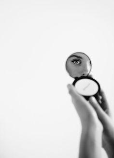 a person holding a magnifying glass in front of their face with both hands