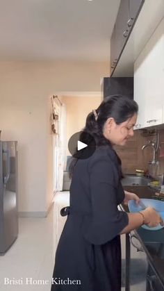 a woman is washing dishes in the kitchen