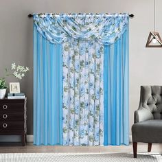 a living room with blue curtains and a chair in front of a window that has flowers on it